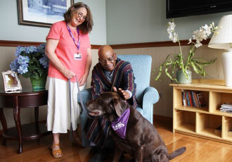 A VITAS PawPals volunteer and her dog visit with a patient