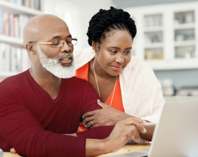 A man and his daughter look at a laptop computer