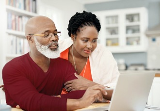 Una mujer y un hombre miran una laptop en su casa