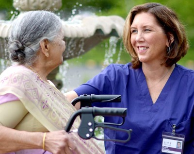 A VITAS team member talks with a female patient outside in a garden