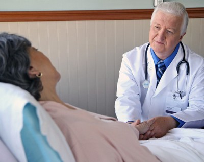 A VITAS physician comforts a patient who is in bed at home