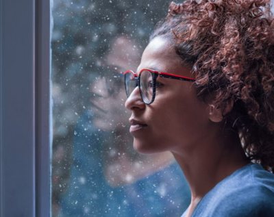 A woman looks out a rainy window