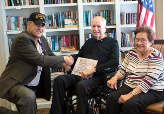 A veteran receives a certificate thanking him for his service during an at-home ceremony