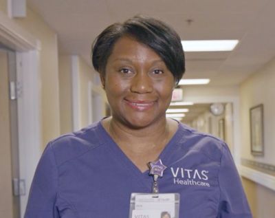 A VITAS nurse smiles in the hallway of an inpatient hospice unit