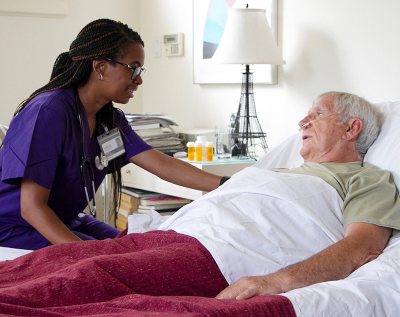 A VITAS team member talks with a patient who is in bed and using oxygen tubes