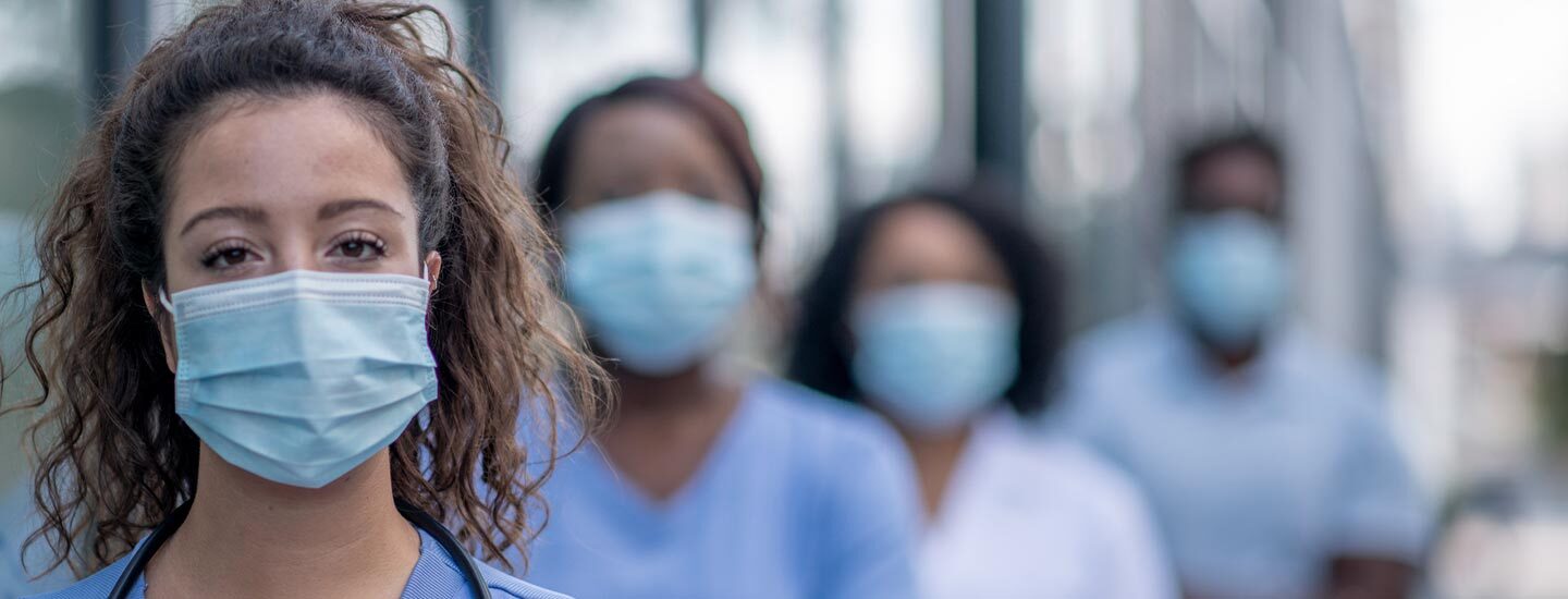 A group of healthcare professionals wearing face masks stands in a staggered line