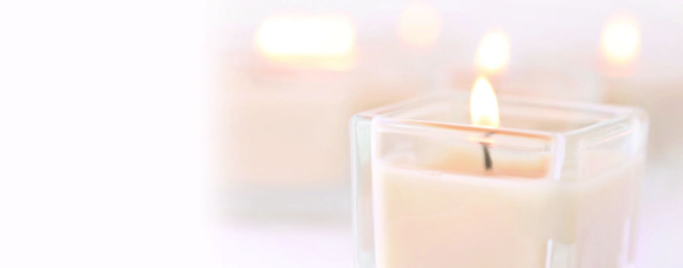 A small collection of white candles glowing on a table