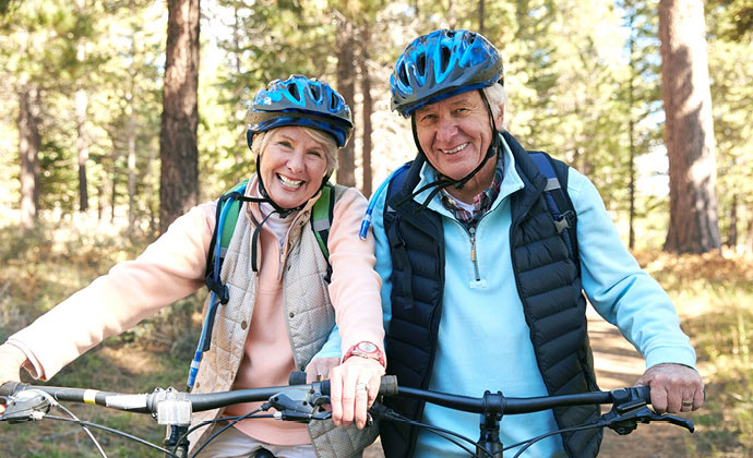A couple rides bicycles on a wooded trail
