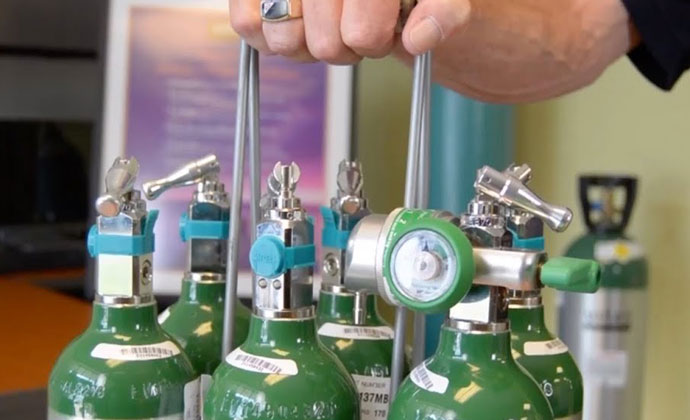 Man handling a rack of oxygen tanks