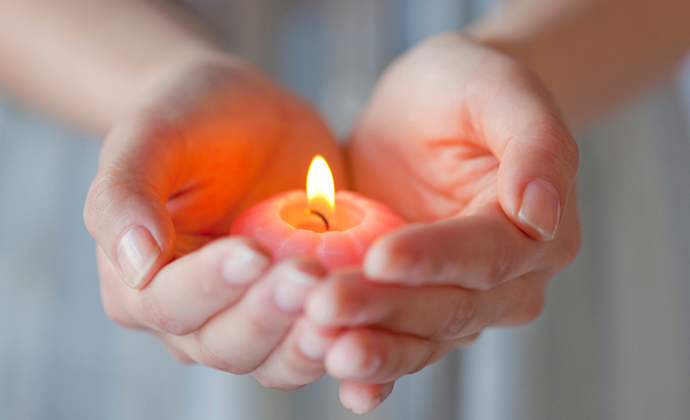 Hands hold a small candle