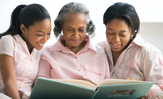 Una mujer mira un álbum de fotos familiares junto a sus dos nietas