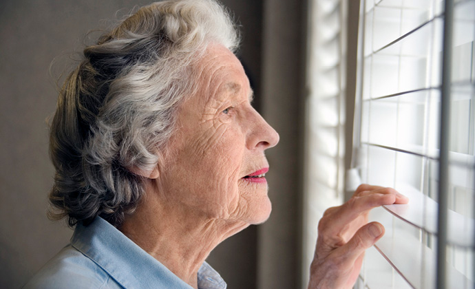 An older woman looks out a window