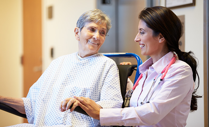 A woman in a wheelchair smiles at her doctor