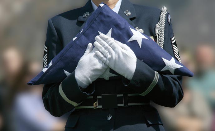 A service member holds a folded flag