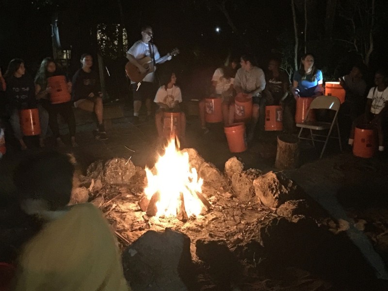 Tom leads the group in songs around the campfire at night