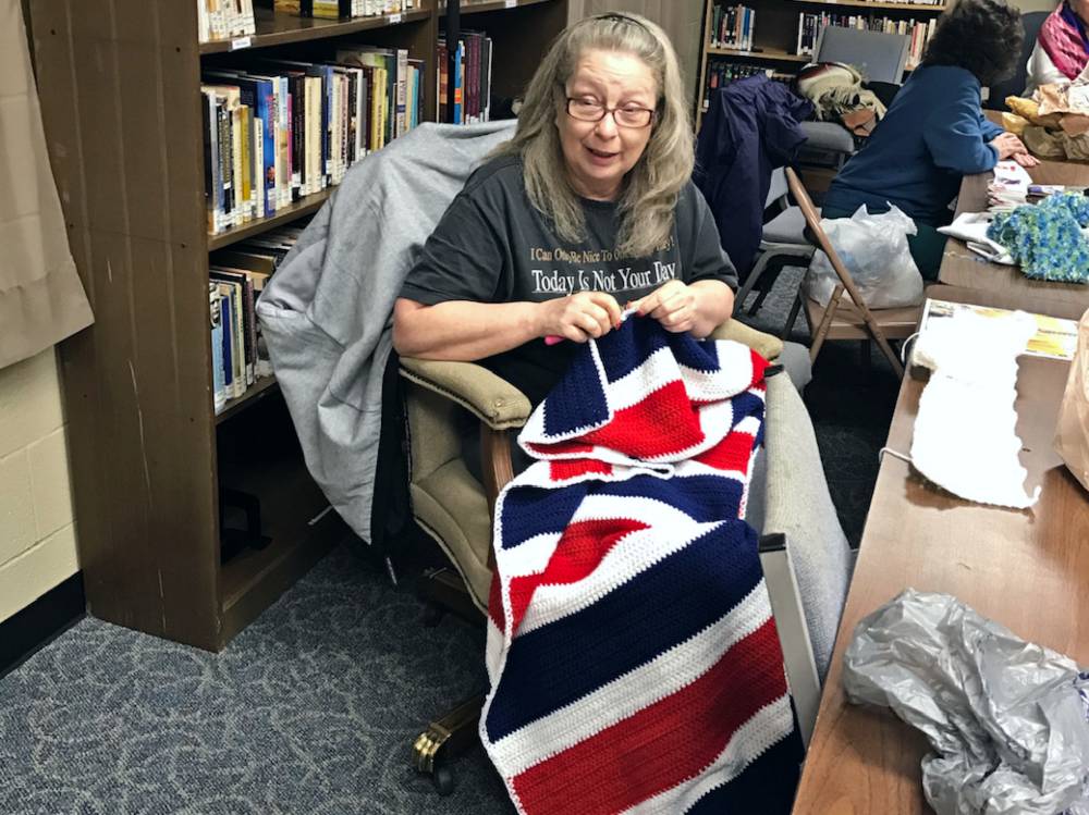 Volunteer Kanda Redding crochets a red, white and blue blanket
