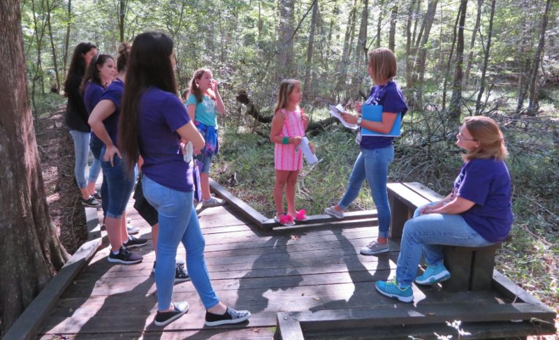 A small group gathers on a path in a forested part of the park