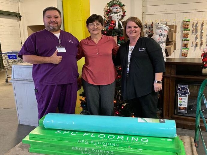 Three team members pose with the flooring materials they donated to Tended Treasures