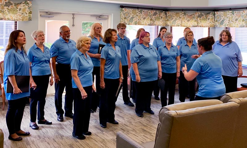The chorus performs in a community room