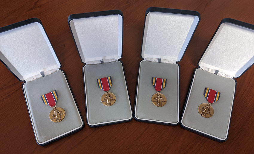 Four World War II Victory Medals displayed on a table before their presentation to VITAS patients