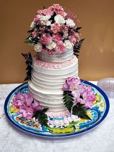The wedding cake topped with a fresh floral arrangement