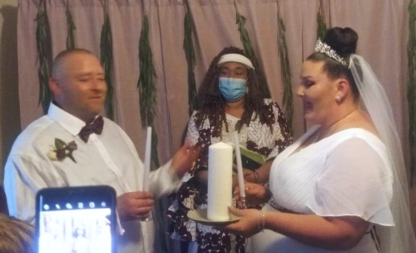 The couple prepares to light the unity candle while the officiant looks on