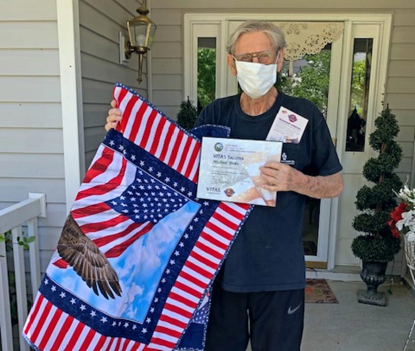 Michael Boiko holds his certificate and quilt on the front porch