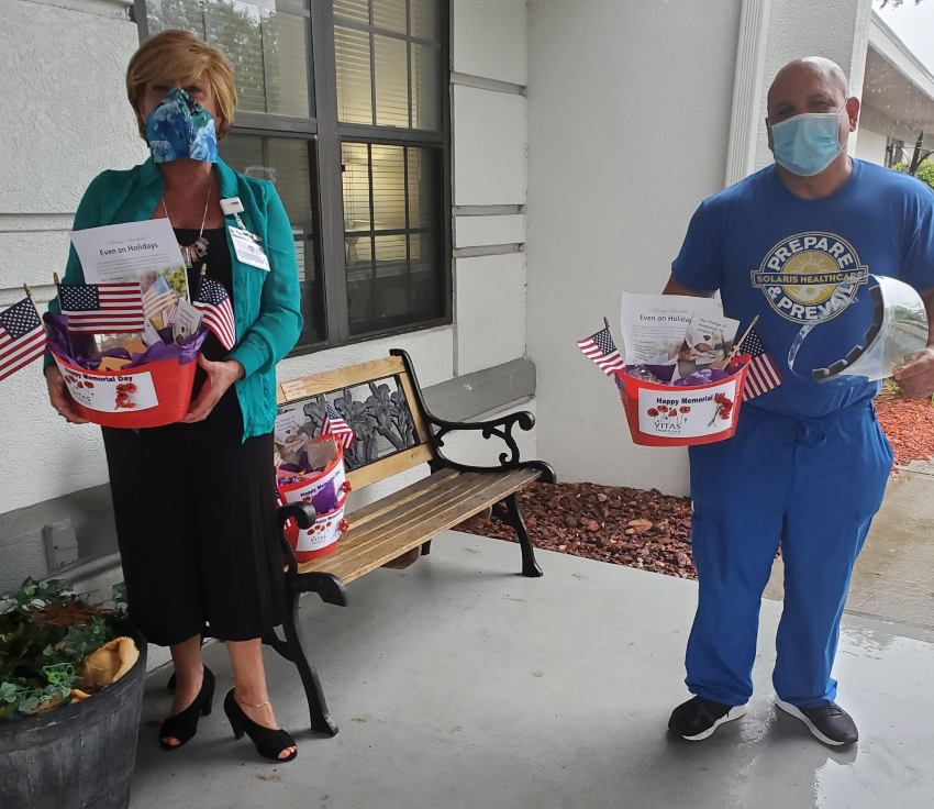 Two people carry Memorial Day baskets into the building