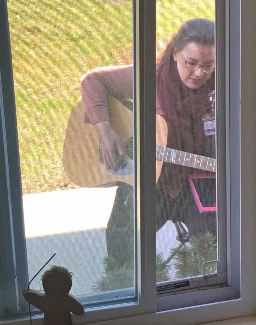 Mia plays guitar outside a window