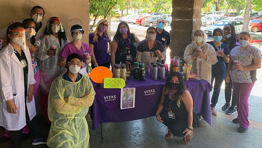The staff, wearing masks, poses at the coffee bar VITAS set up for them