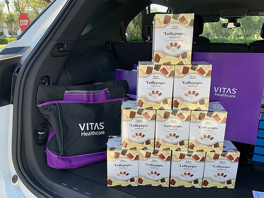 Ten boxes of See's lollipops stacked in the back of the car ready for delivery