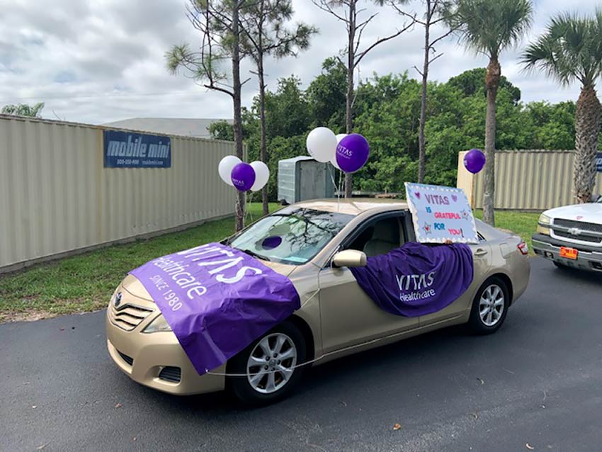 A sedan is covered with purple signs and balloons to celebrate in the parade