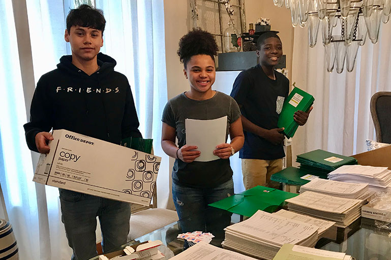 The teen volunteer put together packets at a table at home