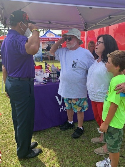 Fred salutes a veteran at the Vietnam and All Veterans Reunion, as the veteran's family looks on