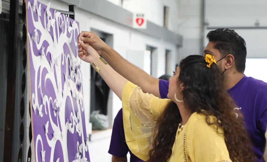 A VITAS team member helps an attendee pin their loved one's name to the board