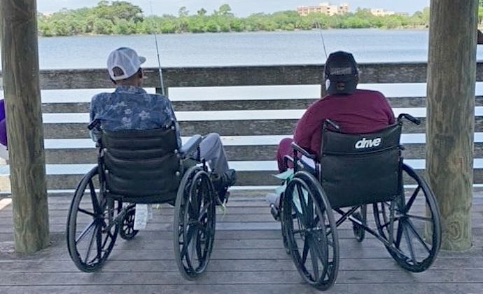 VITAS patient JC Payne and his wife seated in their wheelchairs as they cast their lines at the fishing dock