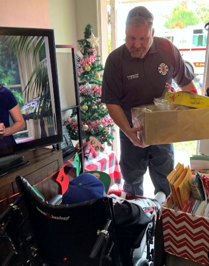 A firefighter carries a box of Christmas cards into Nicholas' home