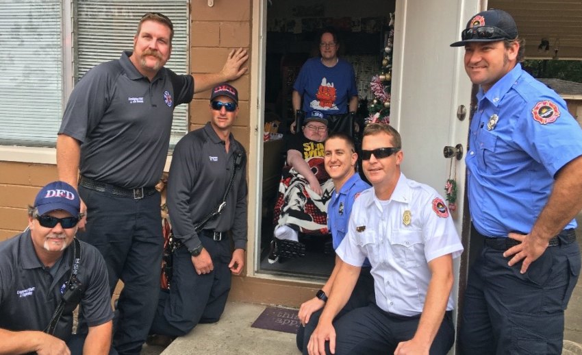 Firefighters pose for a photo with Nicholas and his mother at the front door to their home