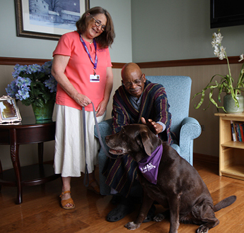 A Paw Pals volunteer brings a dog to comfort a patient