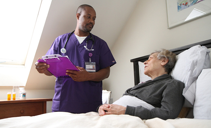 Một y tá của VITAS đang nói chuyện với một bệnh nhân khi bà ấy đang ngồi dậy trên giường