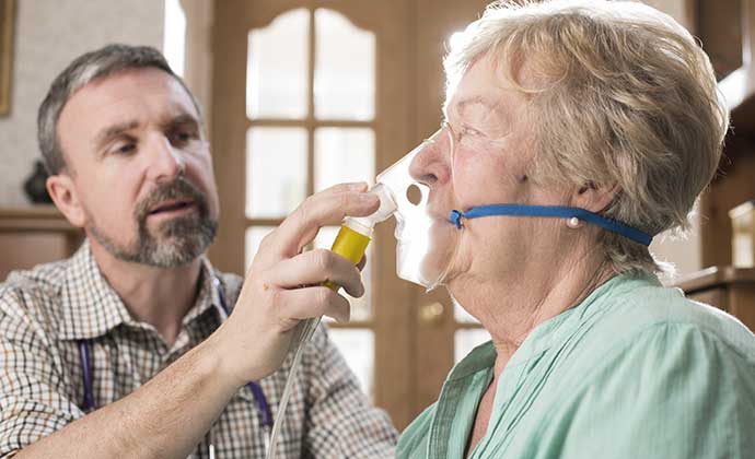 Un terapista respiratorio ayuda a una paciente con la máscara de oxígeno