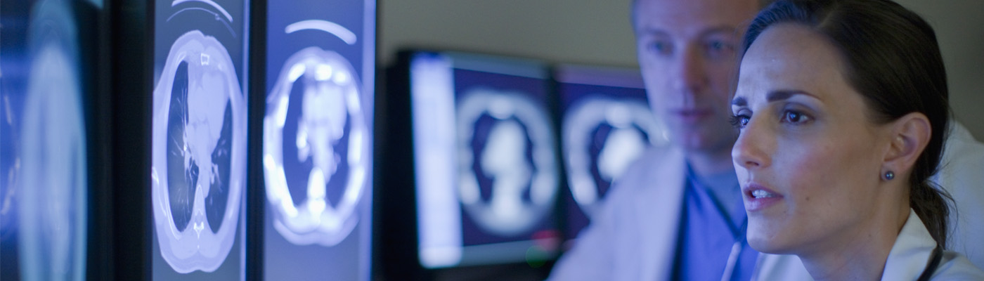 Two physicians look at a series of scans