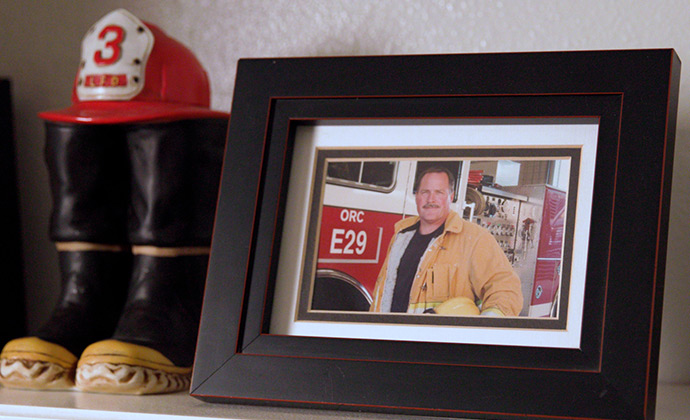 A framed picture of Jim in turnout gear sits next to a miniature of fire boots and helmet