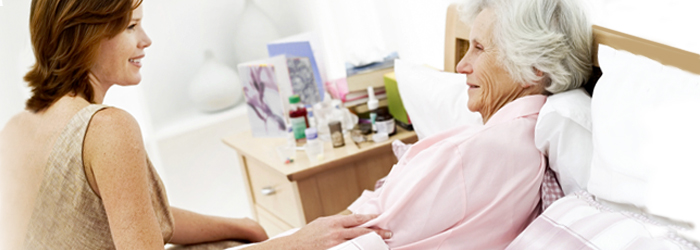 Caretaker and patient smiling on the side of the bed