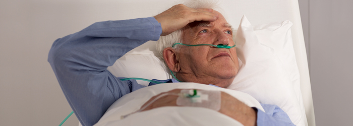 Patient in bed with oxygen in nose rubbing head