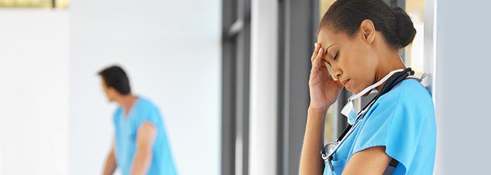 Distraught healthcare professional with hand on her forehead