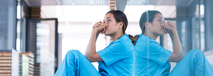 Hospice worker leaning against wall distressed