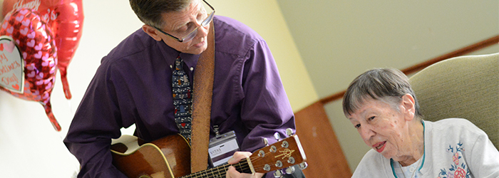 VITAS caretaker playing guitar for hospice patient