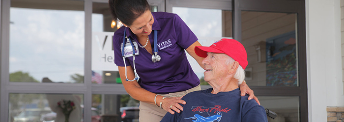 VITAS caretaker smiling at patient in red hat