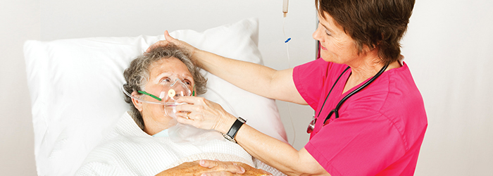 Caretaker puts oxygen mask on bedridden patient